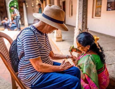 A traveller getting henna done by a local in South India on a classic tour